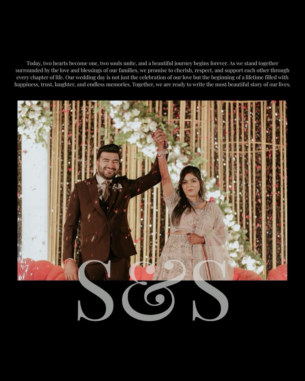 The couple raise their joined hands on the reception stage amid falling petals