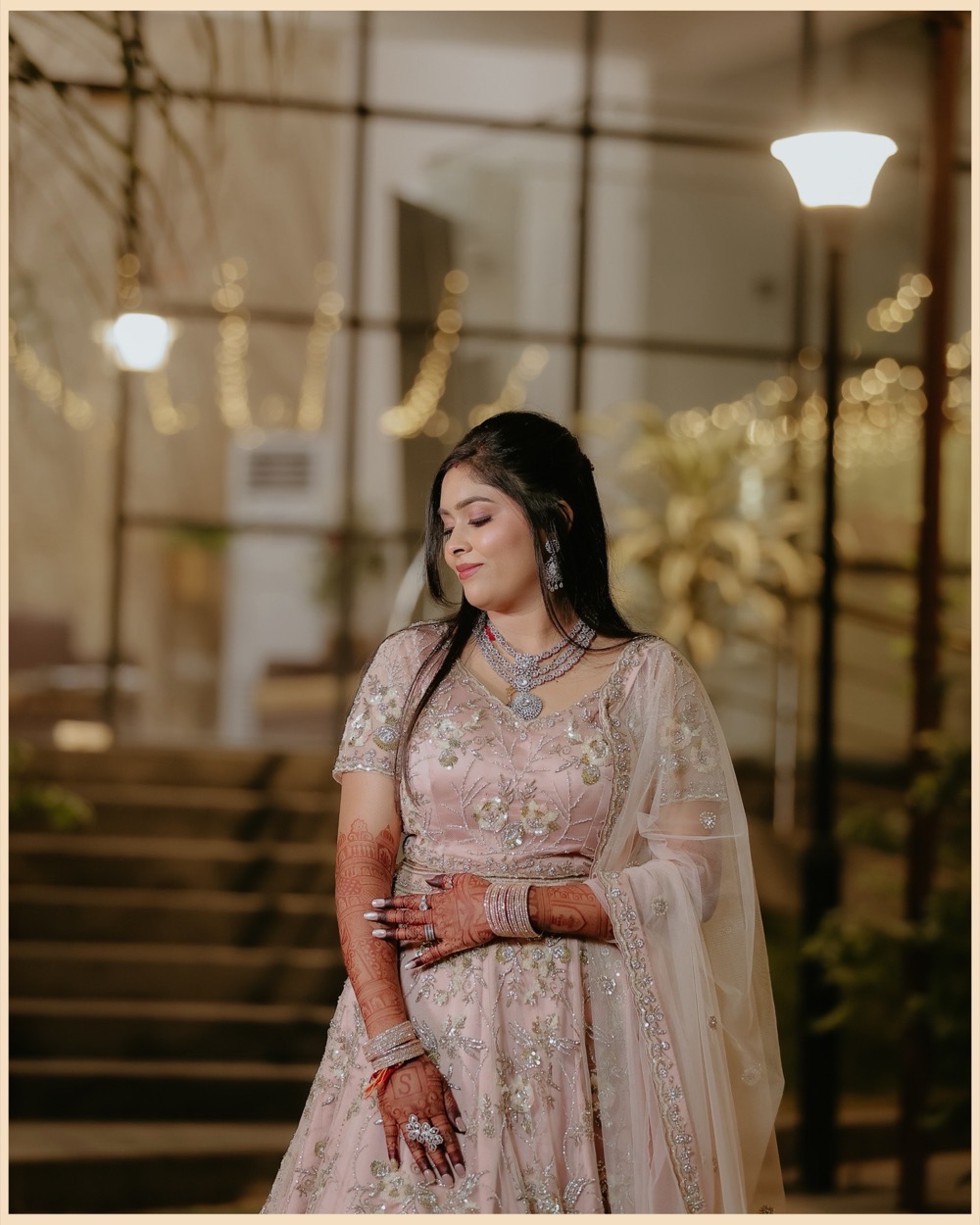 Bride in a blush lehenga photographed at night beside a lamp post